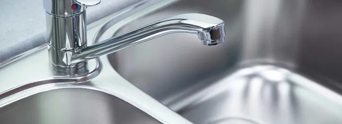 Un primer plano de un fregadero de cromo o aluminio y un grifo