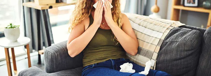 Mujer con síntomas de alergia al resfriado sonándose la nariz