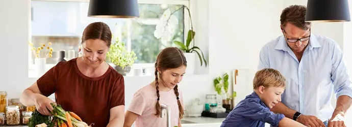 Una madre y un padre enseñando reciclaje para niños, desempaquetando comida de envases reciclables en una cocina
