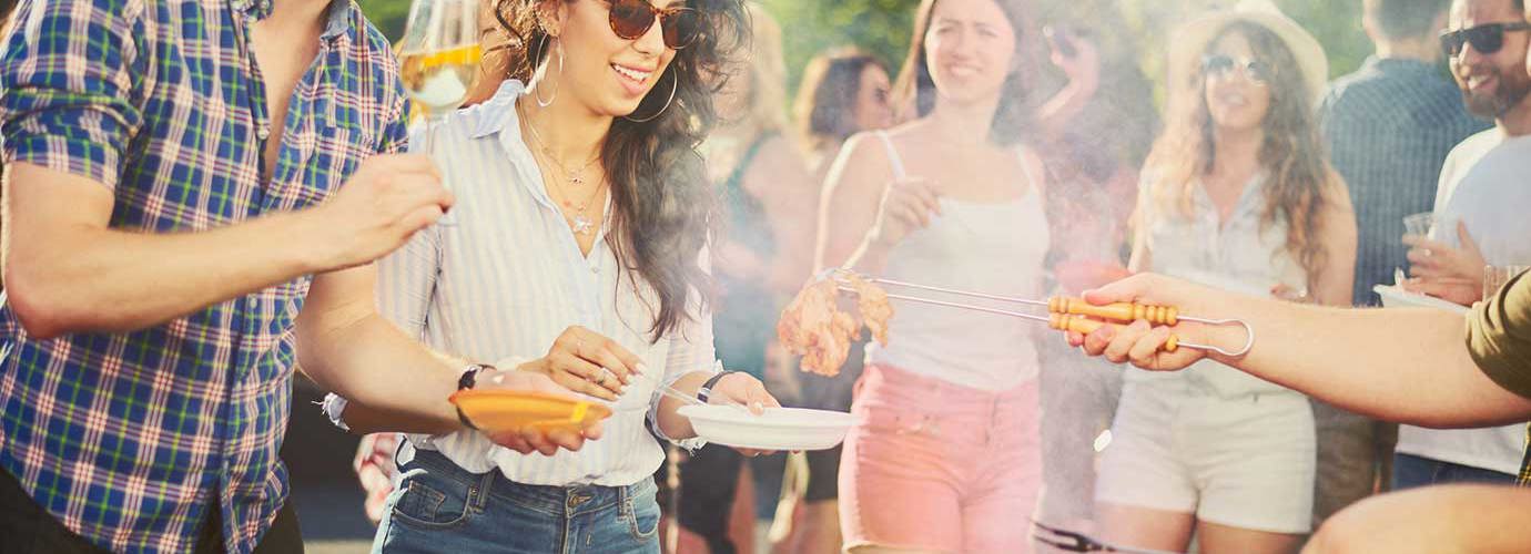 Un grupo de amigos en una fiesta barbacoa alrededor de una parrilla de barbacoa