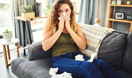 Mulher com sintomas de alergia ou constipação a assoar o nariz