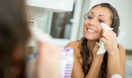 Mulher a sorrir enquanto remove a maquilhagem com um lenço facial