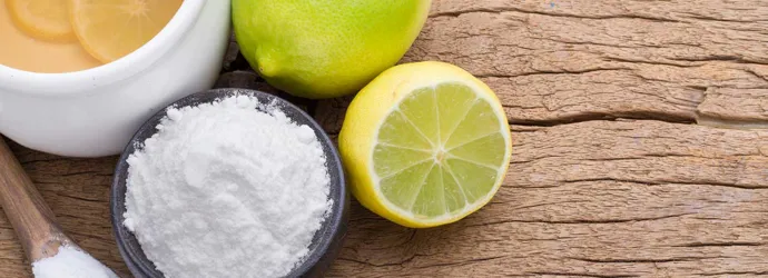 Produtos de limpeza ecológicos, como limão, lima e bicarbonato de sódio numa tábua de madeira