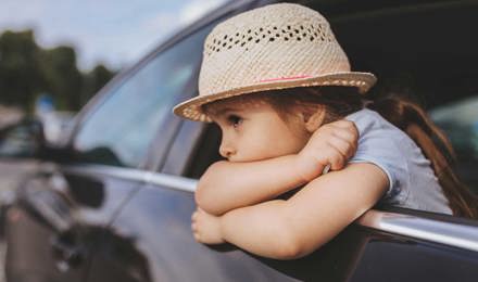 Criança enjoada num carro a usar um chapéu